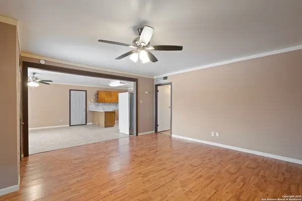 a view of empty room with wooden floor and ceiling fan