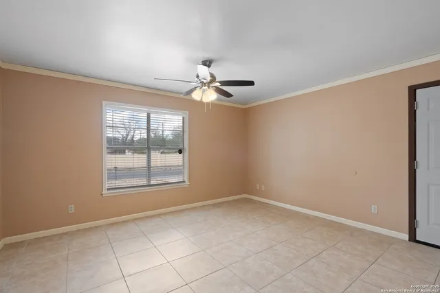an empty room with chandelier fan and windows