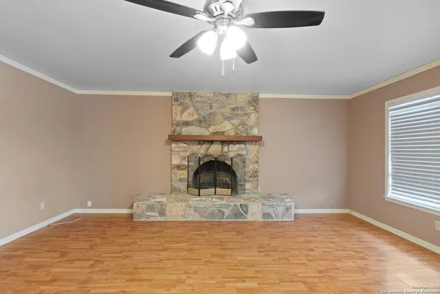 a view of a livingroom with a fireplace a ceiling fan and wooden floor
