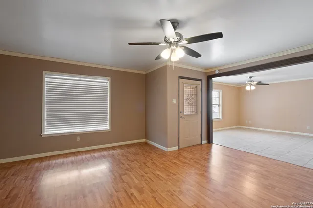 a view of an empty room with wooden floor and a window