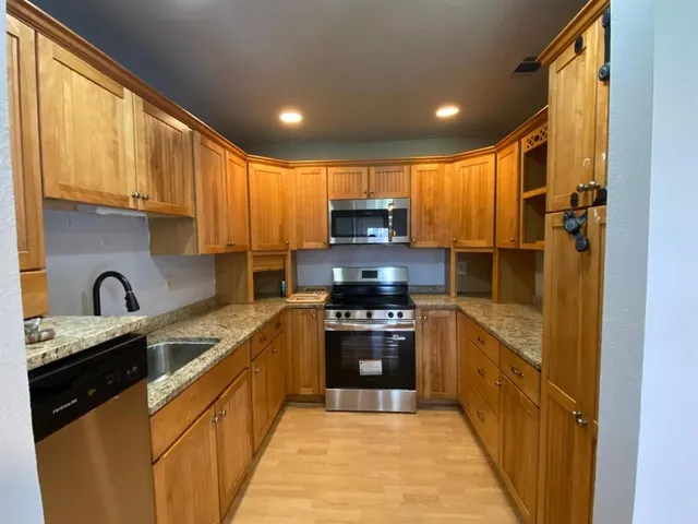 a kitchen with stainless steel appliances granite countertop a refrigerator a sink dishwasher a stove and a microwave oven with cabinets