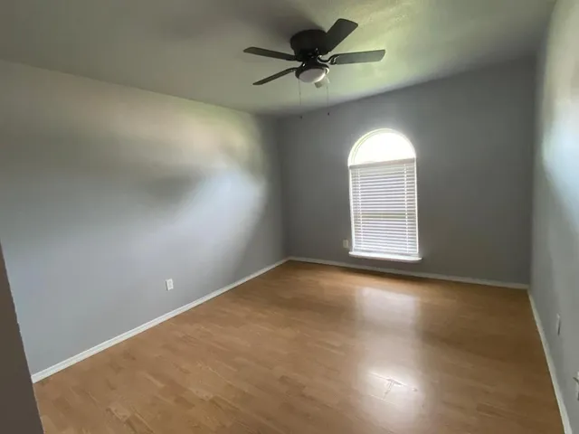 an empty room with a window and a fan