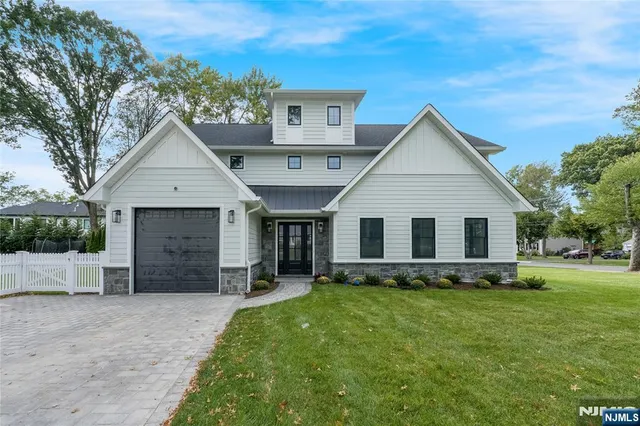 a front view of house with yard and trees in the background