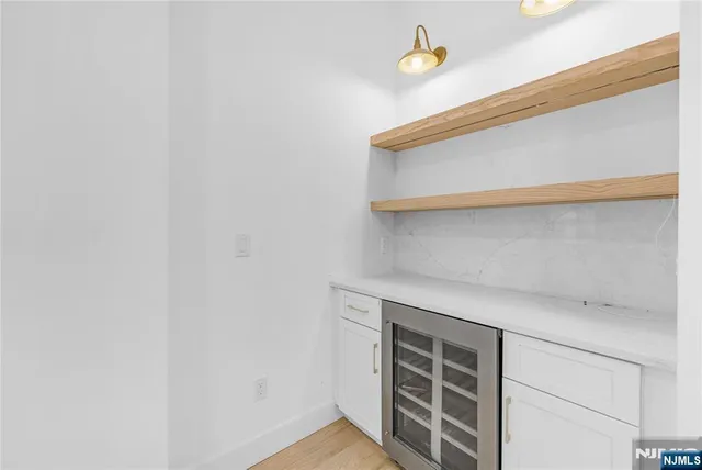 a kitchen with stainless steel appliances kitchen island granite countertop a refrigerator a oven a sink and white cabinets with wooden floor