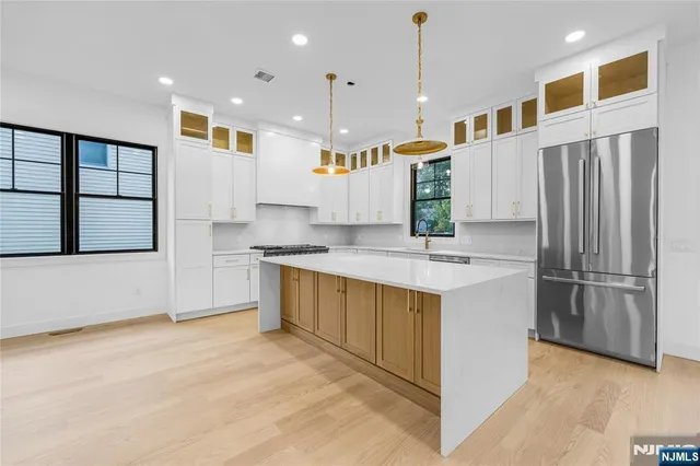 a kitchen with stainless steel appliances granite countertop a sink a oven a dining table and chairs with wooden floor