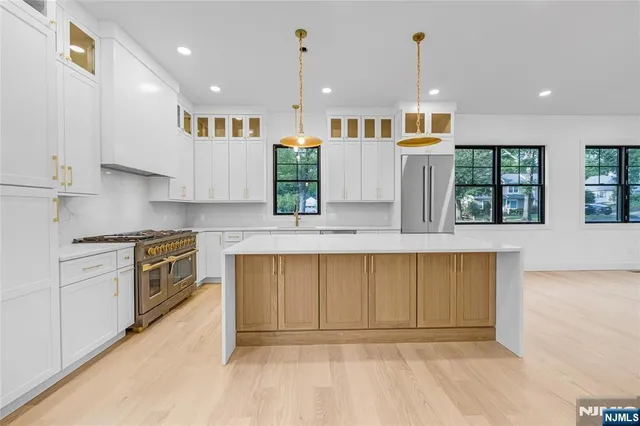 a large kitchen with stainless steel appliances granite countertop a sink a stove and a refrigerator
