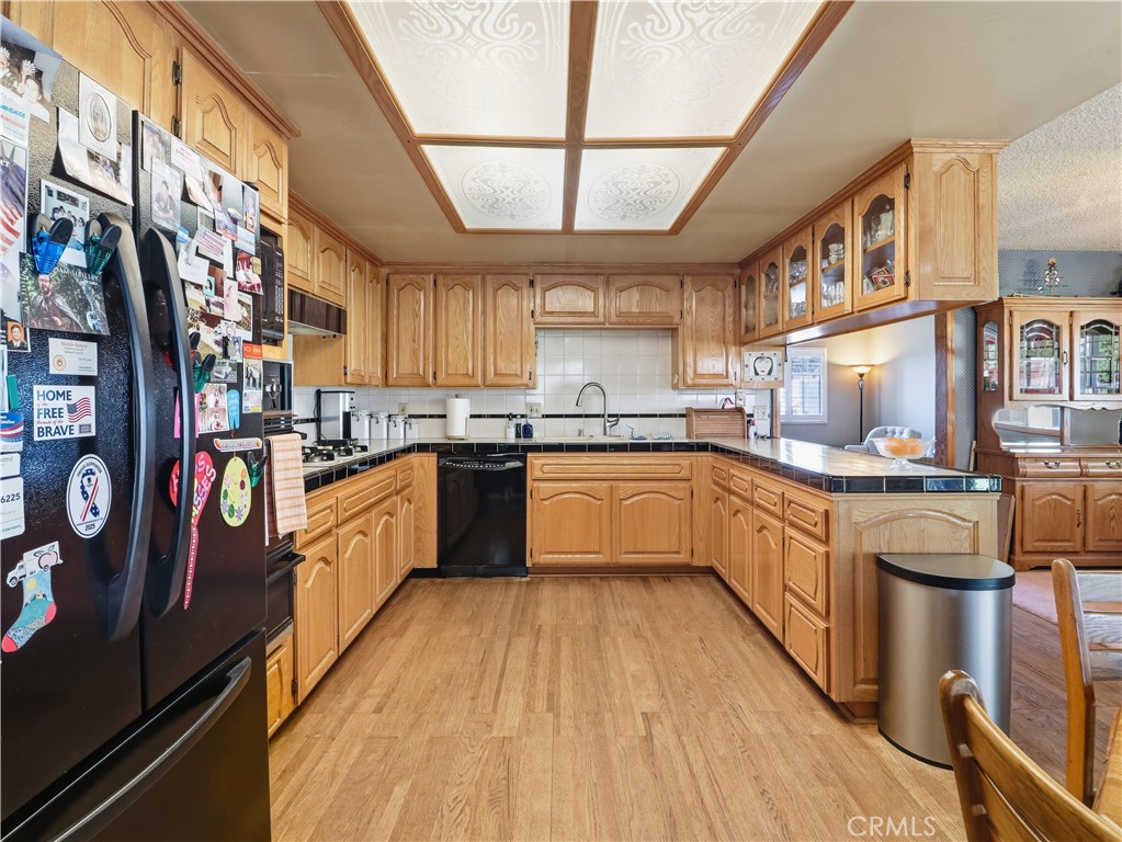10930 Rio Hondo Drive Downey, CA 90241 - Photo 10 of 30 a kitchen with stainless steel appliances granite countertop a stove a sink dishwasher and white cabinets with wooden floor