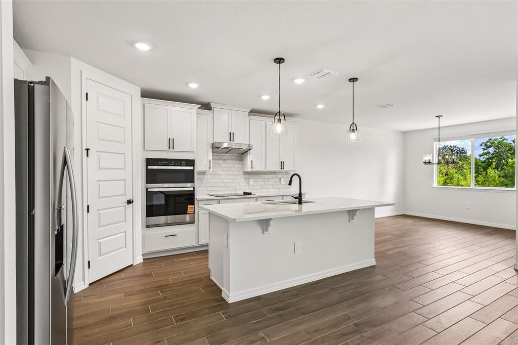 3335 Orchard Loop Bartow, FL 33830 - Photo 15 of 47 a kitchen with stainless steel appliances kitchen island wooden floors and white cabinets