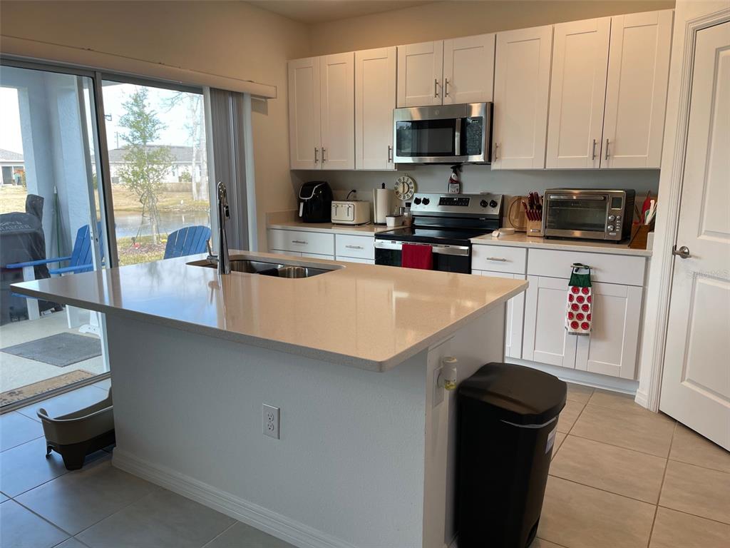 365 River Front Way Edgewater, FL 32141 - Photo 12 of 34 a kitchen with a sink a microwave and wooden cabinets