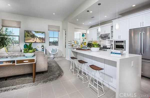 a living room with stainless steel appliances granite countertop furniture a couch a table and a refrigerator