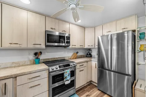 a kitchen with a stove a refrigerator and a dining table with wooden floor