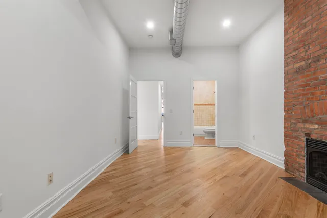 an empty room with wooden floor and a fireplace