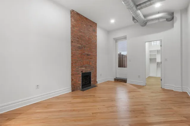 an empty room with wooden floor and fireplace