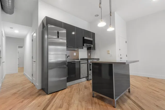 a kitchen with stainless steel appliances a refrigerator and a hard wood floor