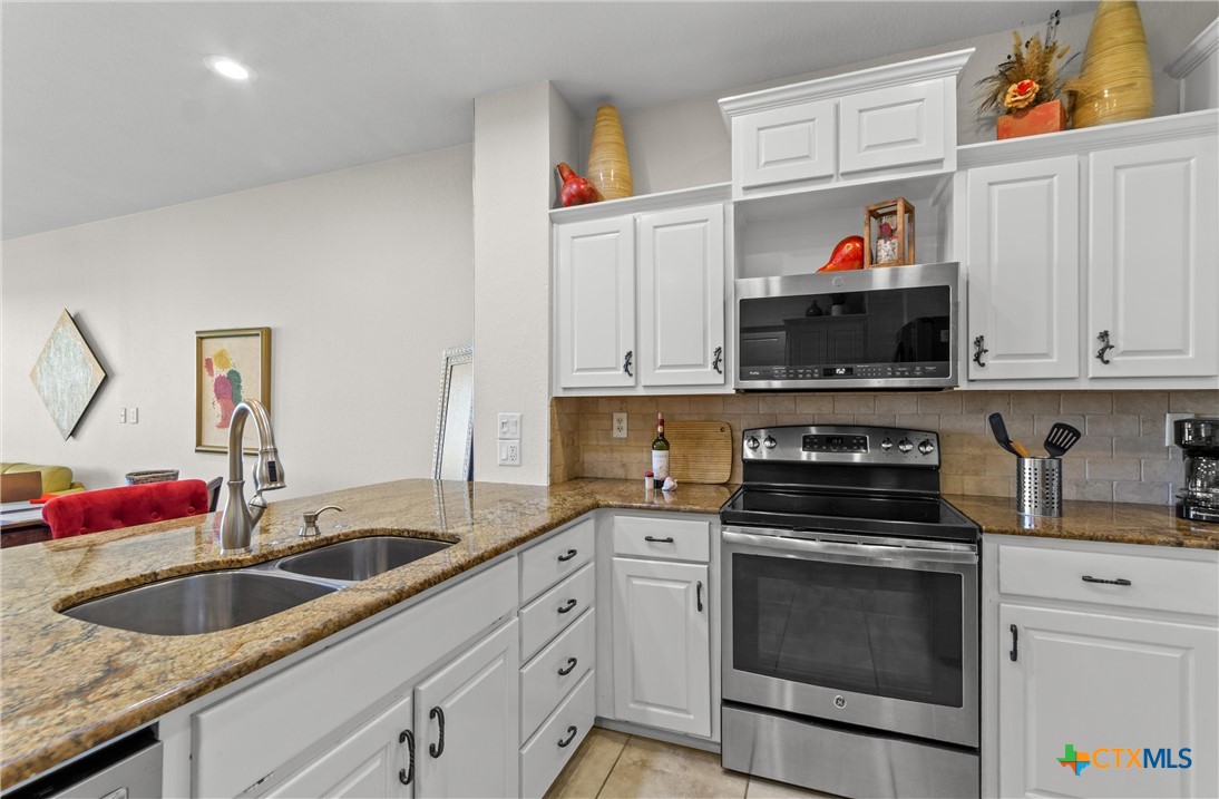 130 Sobrante Road, Unit 209 Belton, TX 76513 - Photo 11 of 36 a kitchen with white cabinets a sink and dishwasher with wooden floor
