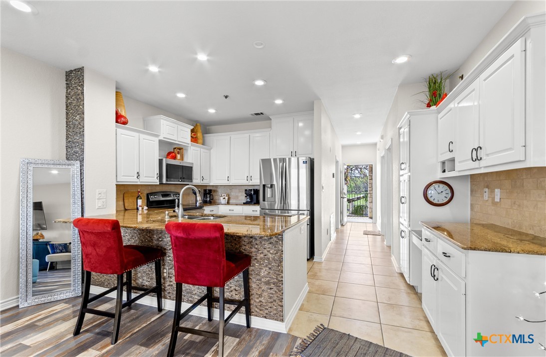 130 Sobrante Road, Unit 209 Belton, TX 76513 - Photo 10 of 36 a kitchen with stainless steel appliances kitchen island granite countertop a table chairs refrigerator and microwave