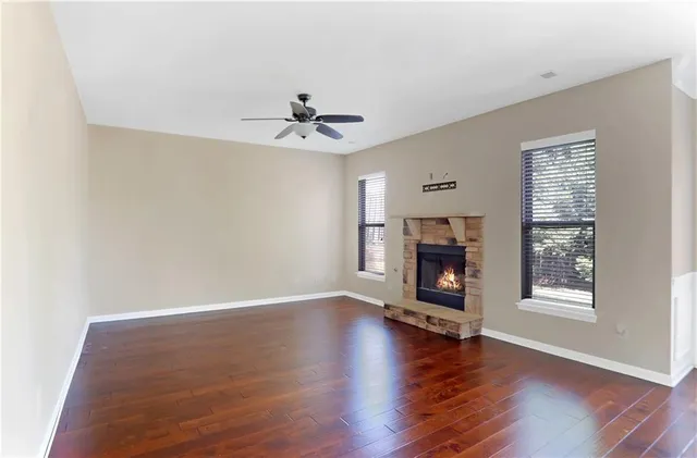 a view of a room with wooden floor fireplace and windows