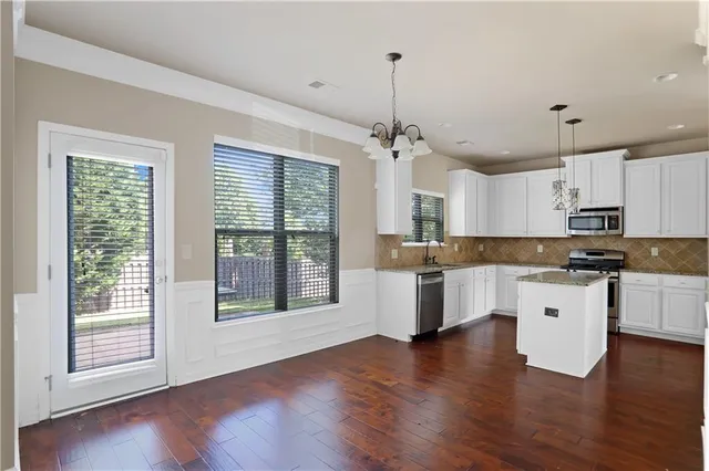 a large kitchen with cabinets wooden floor and stainless steel appliances
