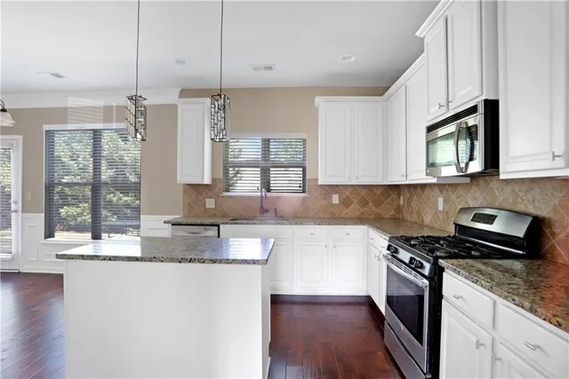 a kitchen with stainless steel appliances granite countertop a stove a sink and a microwave