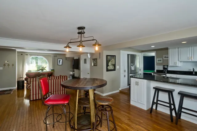 a kitchen with stainless steel appliances kitchen island granite countertop a dining table chairs and white cabinets