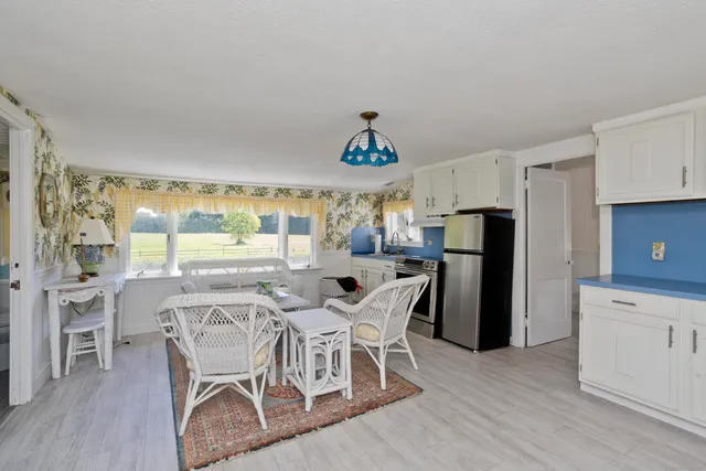 a dining room with furniture a large window and stainless steel appliances