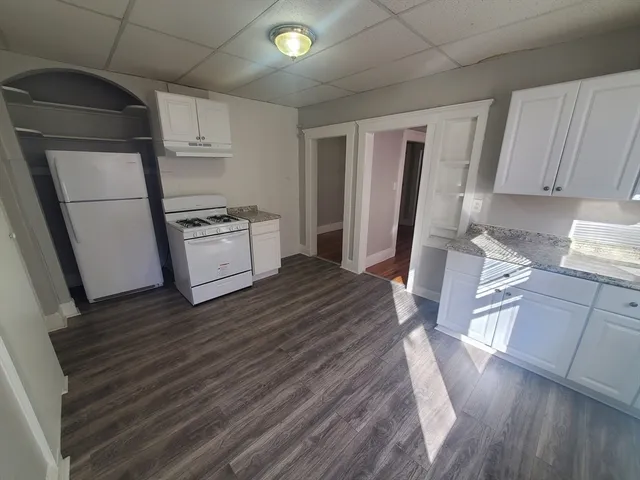 a kitchen with a refrigerator a stove top oven and wooden floor
