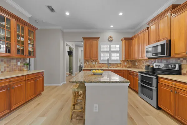 a kitchen with stainless steel appliances granite countertop wooden cabinets a sink and dishwasher a oven with wooden floor