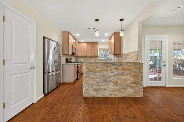 a kitchen with stainless steel appliances granite countertop wooden cabinets a sink and dishwasher a stove with wooden floor