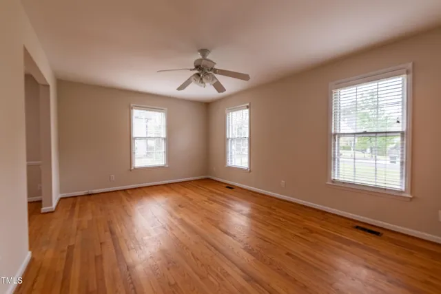 a view of an empty room with wooden floor and a window