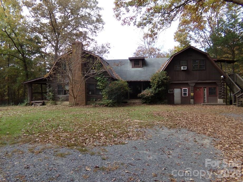 a view of a house with a yard and large tree