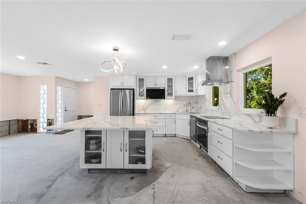 24 Rivard Road, Unit 12 Naples, FL 34112 - Photo 11 of 27 Kitchen with exhaust hood, appliances with stainless steel finishes, a kitchen island, pendant lighting, and white cabinets