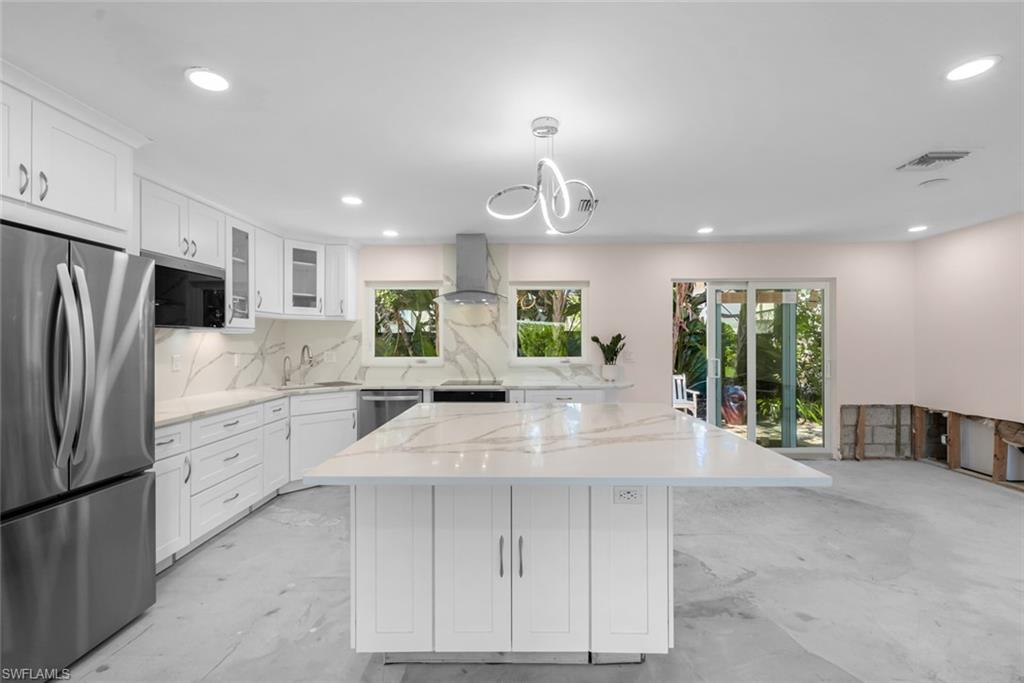 Kitchen featuring white cabinetry, appliances with stainless steel finishes, sink, and wall chimney range hood