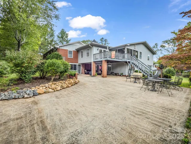 a view of a white house with a big yard and large trees
