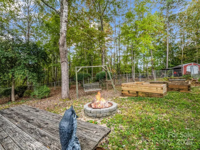 a view of a backyard with table and chairs potted plants and large tree