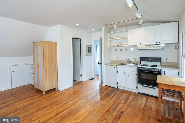 a kitchen with stainless steel appliances a stove top oven a refrigerator a sink and dishwasher with wooden floor