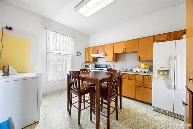 a kitchen with a table chairs refrigerator and a window