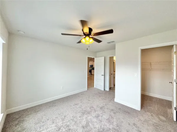 a view of an empty room with a ceiling fan and window