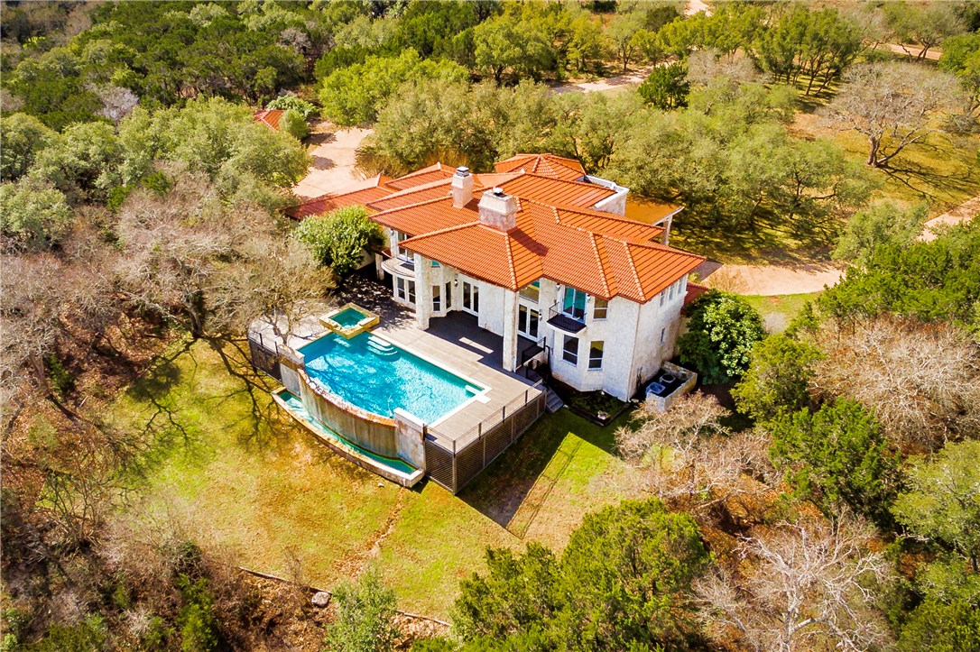 an aerial view of a house with swimming pool and large trees