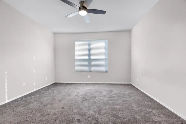 an empty room with a window and a fan