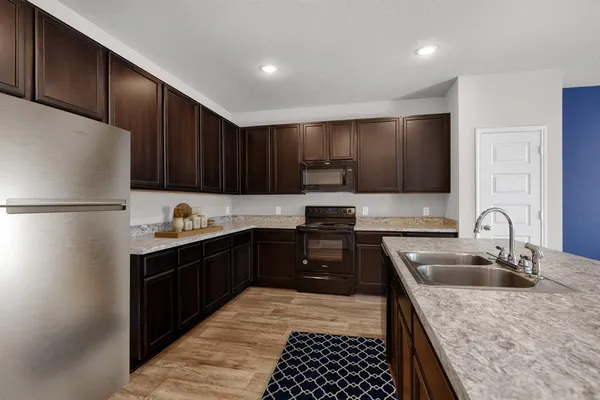 a kitchen with granite countertop a refrigerator stove top oven and sink
