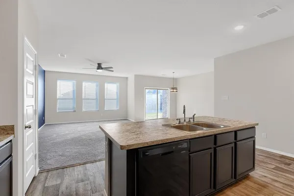 a hall with kitchen island a sink granite counter tops and a view of living room