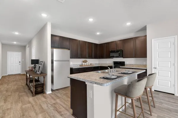 a kitchen with stainless steel appliances granite countertop a refrigerator a stove a sink a dining table and chairs