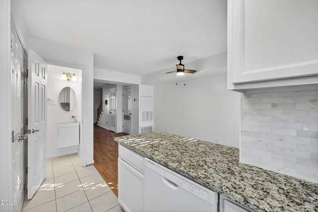 a kitchen with stainless steel appliances granite countertop a refrigerator sink stove and white cabinets