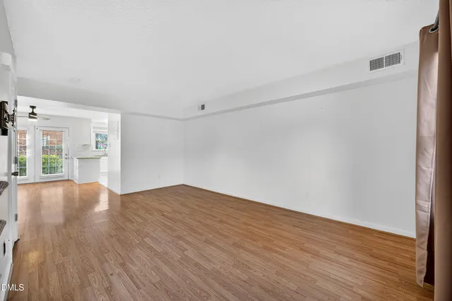 a view of an empty room with window and wooden floor