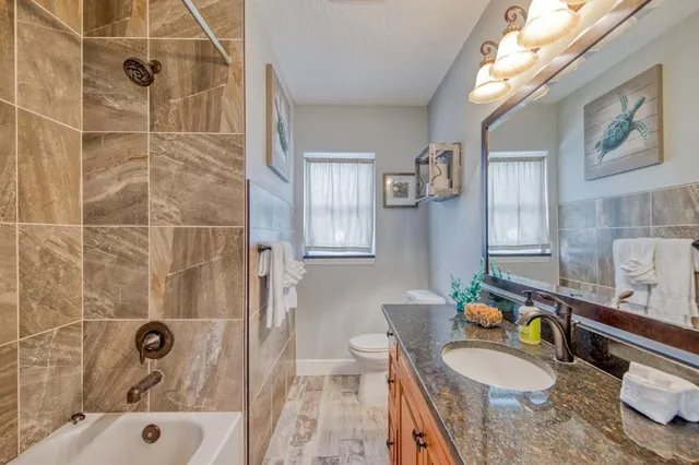 a bathroom with a granite countertop bathtub a sink a toilet and shower