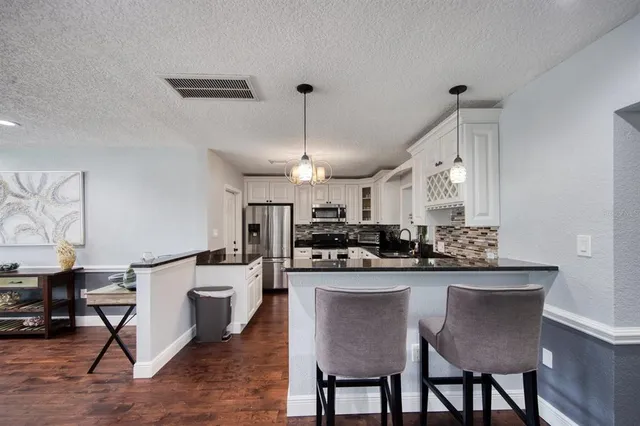a kitchen with stainless steel appliances kitchen island granite countertop a dining table chairs and white cabinets