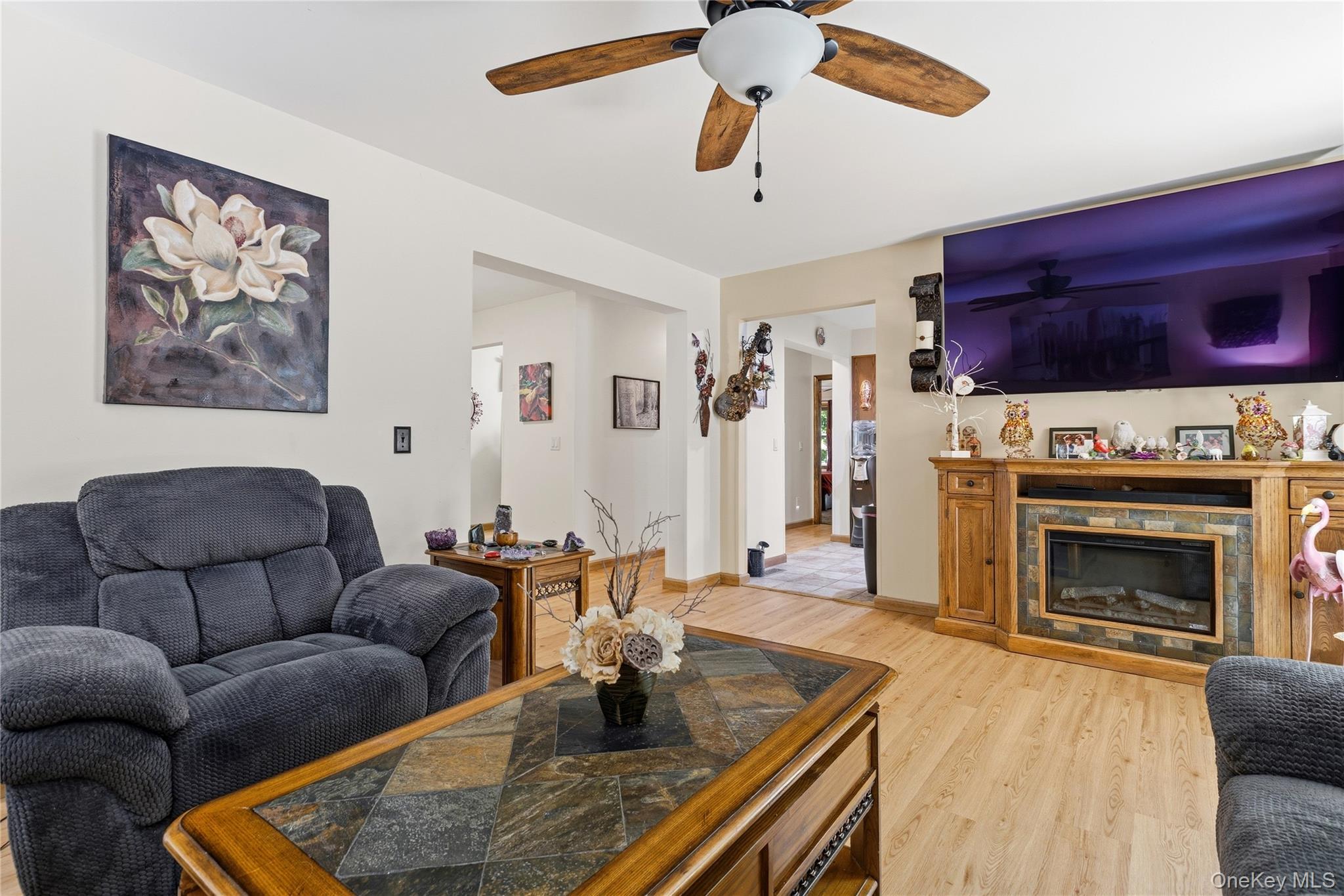 239-241 Fosler Road Highland, NY 12528 - Photo 13 of 42 Living area with light wood-finish flooring, a ceiling fan with integrated lighting, and a built-in media console featuring a fireplace insert