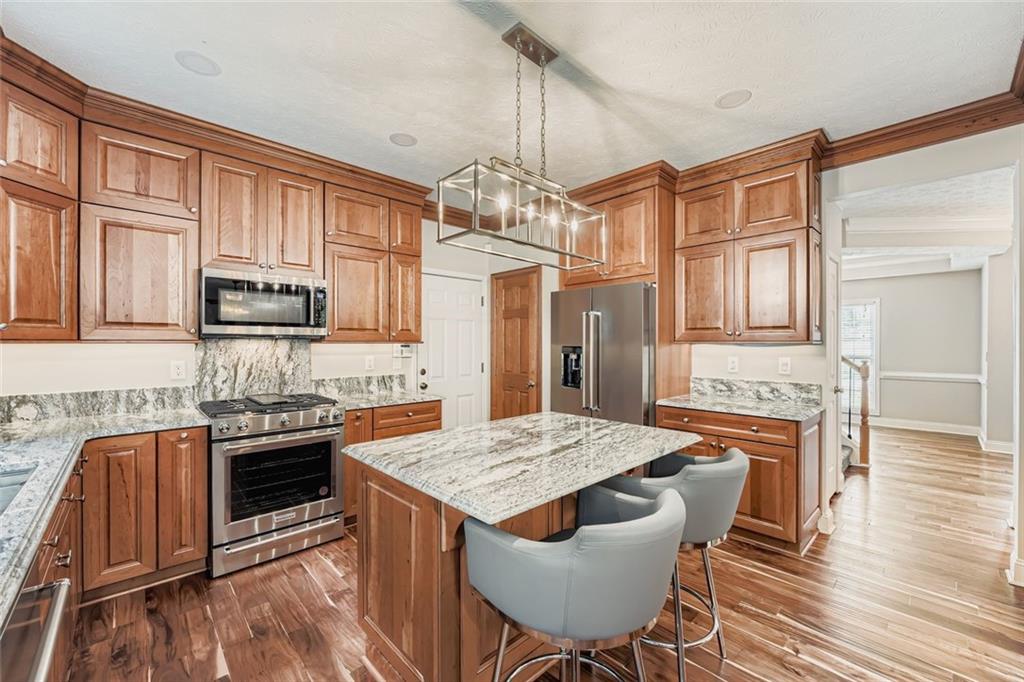 2409 Caneridge Way Southwest Marietta, GA 30064 - Photo 9 of 28 a kitchen with stainless steel appliances granite countertop a stove top oven a sink dishwasher a dining table and chairs with wooden floor