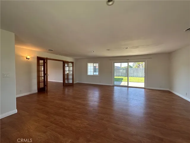 a view of an empty room with window and wooden floor
