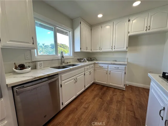 a kitchen with a sink cabinets wooden floor and a window